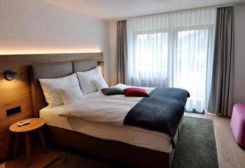 a bed in a hotel room with a large window at Hotel Bernina in Pontresina