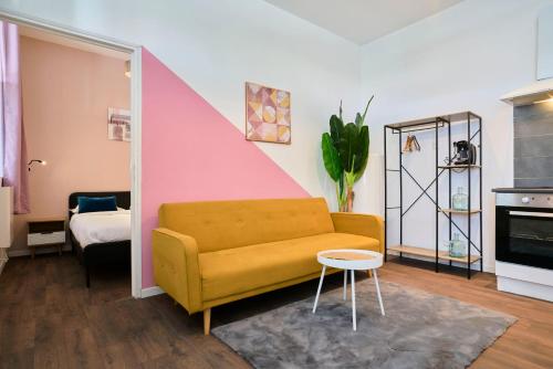 - un salon avec un canapé jaune et un mur rose dans l'établissement NG Prestige - Lille I Tourcoing Winoc - Appartement T2 - Netflix - Wifi - Cuisine - Parking gratuit, à Tourcoing