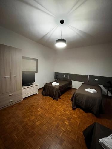 a room with two beds and a flat screen tv at R&B Emilia in Cadeo