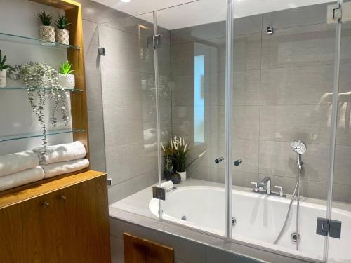 a bathroom with a tub and a glass shower at C Tower Premium Apartments, Panoramic Sea View in Netanya