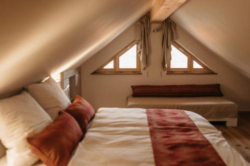 a attic bedroom with a bed and two windows at Gronewald's Mountain View Holidays in Grünenbach