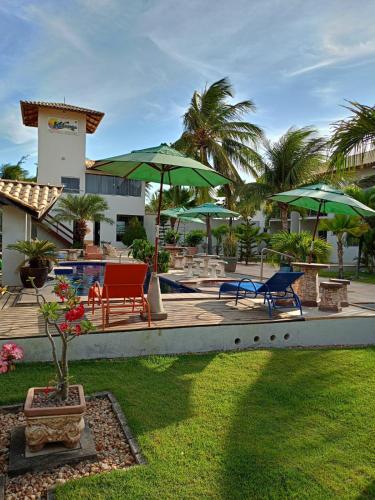 a resort with a pool with chairs and umbrellas at Pousada Kalunga in Flecheiras