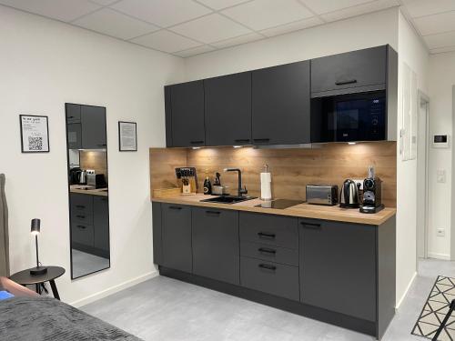 a kitchen with black cabinets and a counter top at SweetHome - Studio Apartment Ergolding in Ergolding