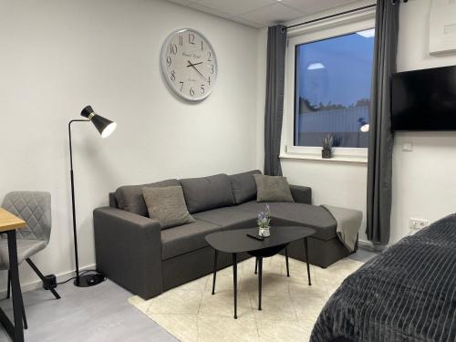 a living room with a couch and a clock on the wall at SweetHome - Studio Apartment Ergolding in Ergolding