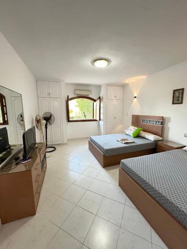 a bedroom with two beds and a television in it at شاليه vip مارينا 5 الساحل الشمالي العلمين in El Alamein