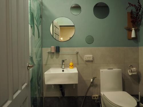 a bathroom with a sink and a toilet and a mirror at Seamoon House in Tainan