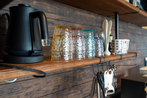 a shelf with glasses and utensils on it at アワセベイストリートホテル in Okinawa City