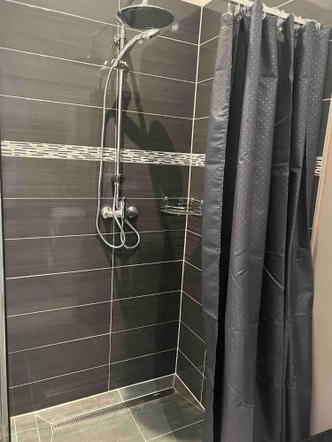 a shower in a bathroom with a black shower curtain at Appartements Bel Lago Bestensee in Bestensee