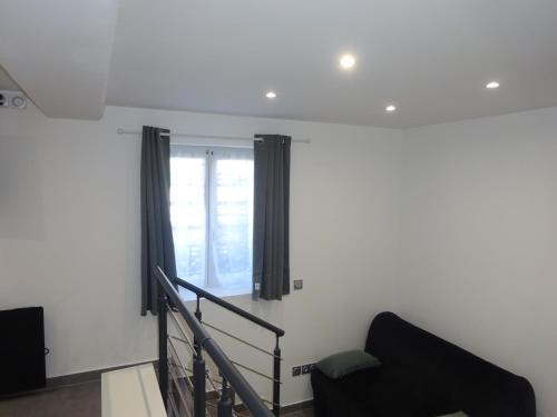 - un salon avec une chaise noire et une fenêtre dans l'établissement studio a 2 mins du palais de la musiques et des congrès, à Strasbourg
