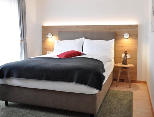 a bedroom with a large bed with white and red pillows at Hotel Bernina in Pontresina