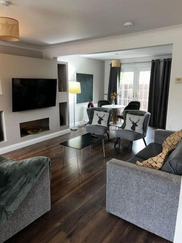a living room with couches and a table and a television at 15 min drive to airport 20 min to Loch Lomond and city center in Old Kilpatrick