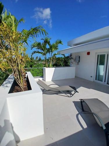 a patio with two chairs and trees and a building at En Plaza Center Penthouse con 3 terrazas en el centro de Las Terrenas la playa està a 5 min a pied in Las Terrenas