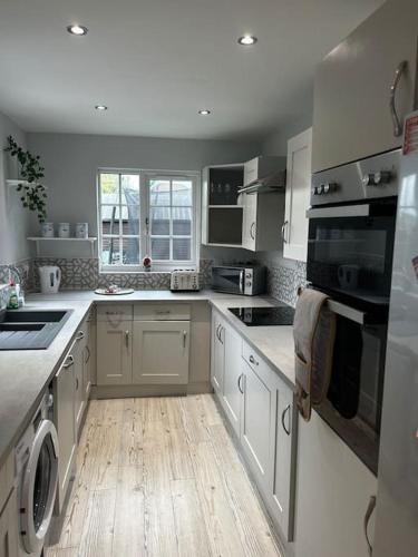 a kitchen with white cabinets and a wooden floor at 15 min drive to airport 20 min to Loch Lomond and city center in Old Kilpatrick