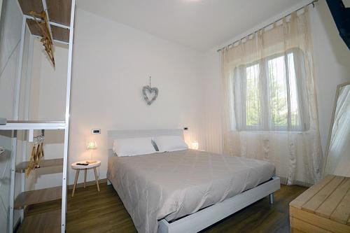 a white bedroom with a bed and a window at Casa Parisina in Chianciano Terme