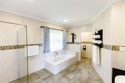 a bathroom with a bath tub and a window at 8 On Eagle Bed & Breakfast Room 1 in Umtentweni