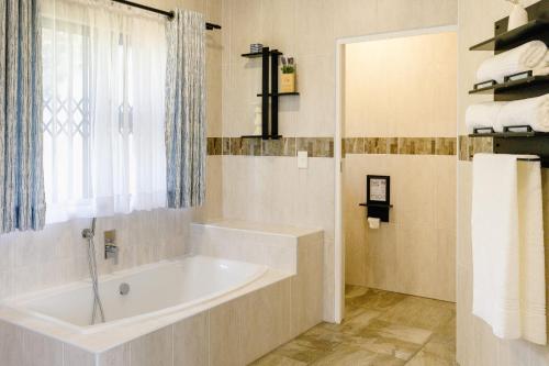 a bathroom with a bath tub and a window at 8 On Eagle Bed & Breakfast Room 1 in Umtentweni