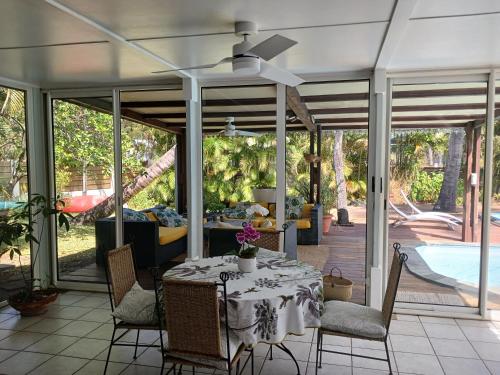 a dining room with a table and chairs on a patio at La villa de Claude, charmante villa créole Etang Salé les Bains in Étang-Salé les Bains