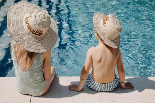 two children wearing hats sitting next to a swimming pool at Domaine De Manville in Les Baux-de-Provence