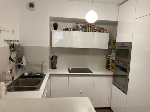 une cuisine blanche avec un évier et une cuisinière dans l'établissement Appt Calme Montreuil limite Vincennes Paris, à Montreuil