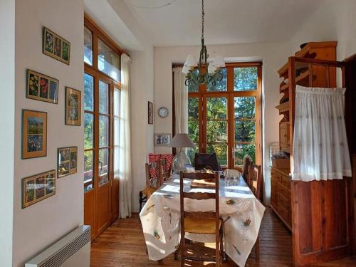 a dining room with a table and some windows at La Chaumière, Formule maison entière in Colmars