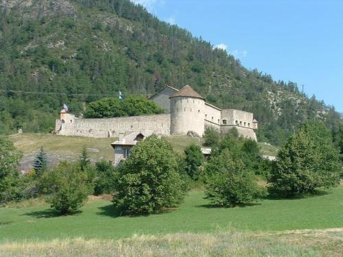 a castle on a hill with trees in a field at La Chaumière, Formule maison entière in Colmars