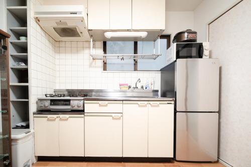 a kitchen with white cabinets and a refrigerator at 錦糸町 in Tokyo
