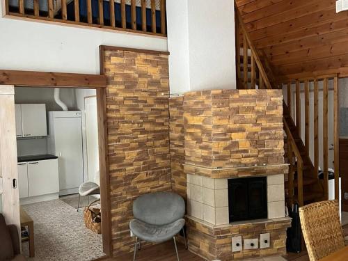 a living room with a brick fireplace with a chair at Karhurinne Koli in Hattusaari