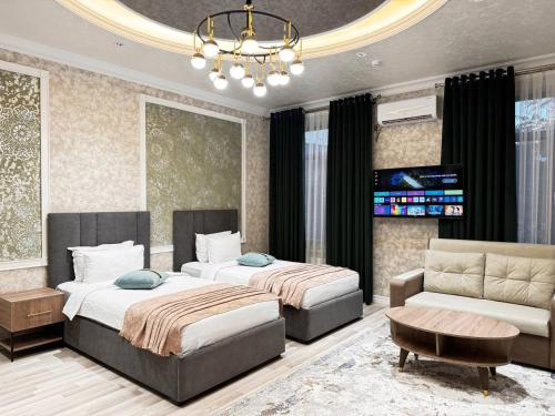 a bedroom with two beds and a couch and a chandelier at HOTEL SILK ROAD EMPIRE SAMARKAND in Samarkand