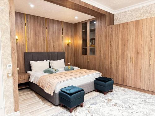 a bedroom with a large bed with two blue ottomans at HOTEL SILK ROAD EMPIRE SAMARKAND in Samarkand