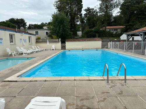 une grande piscine bleue entourée de chaises blanches dans l'établissement Mobilhome 6 personnes, à Saint-Georges-de-Didonne
