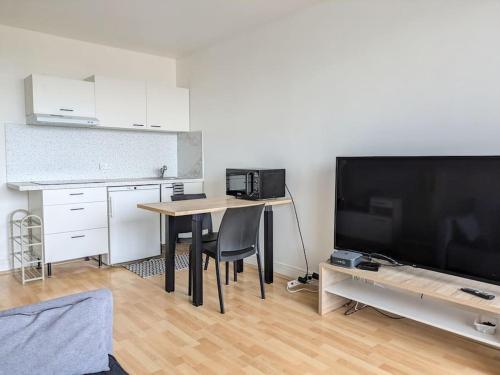 un salon avec une table et une grande télévision dans l'établissement T3 neuf moderne entièrement équipé vue 3 pers, à Saint-Jean-des-Vignes