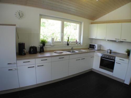 een keuken met witte kasten, een gootsteen en een raam bij Haus Stressfrei - Nordhorn in Nordhorn