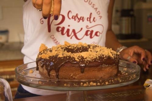 Casa de Paixão Caraíva في كرايفا: شخص يحمل كعكة شوكولاتة على طبق زجاجي