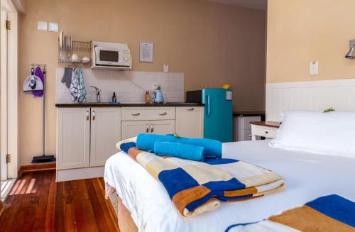 a bedroom with a bed and a kitchen with a refrigerator at Withuis Hartenbos - No Load Shedding in Hartenbos