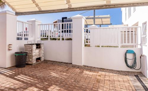 a white house with a white fence and a patio at Withuis Hartenbos - No Load Shedding in Hartenbos