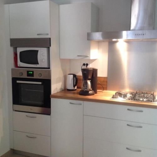 La cuisine est équipée de placards blancs, d'un four micro-ondes et d'une cuisinière. dans l'établissement Les lauriers roses, à La Croix-Valmer