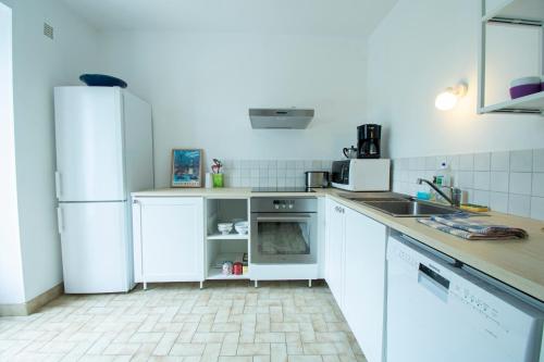 Il comprend une cuisine équipée d'appareils électroménagers blancs et d'un réfrigérateur blanc. dans l'établissement Maison du pécheur I Terrasse & 500m de la mer, à Camaret-sur-Mer