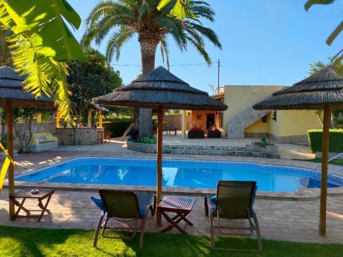 a swimming pool with two chairs and umbrellas at Casa Paula Villas - Private Heated Pool for Each House in Lagos