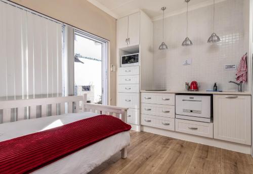 a white bedroom with a bed and a kitchen at Withuis Hartenbos - No Load Shedding in Hartenbos