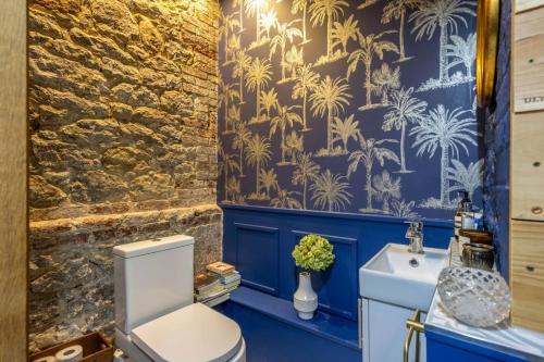 a bathroom with blue walls and a white toilet and a sink at Super Host Large Luxury Cottage South Downs Park in Lodsworth