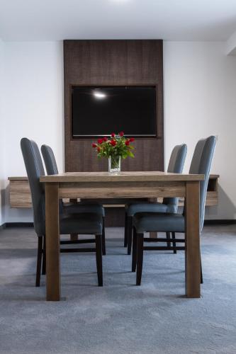 a wooden table with chairs and a vase with flowers on it at Guest House Frizzante in Turčianske Teplice