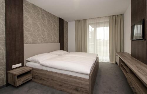 a bedroom with a white bed and a television at Guest House Frizzante in Turčianske Teplice