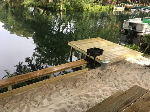 a wooden dock with a bench next to the water at The Chuby Mermaid - Weeki Wachee River Access Waterfront with Paddlecraft in Spring Hill