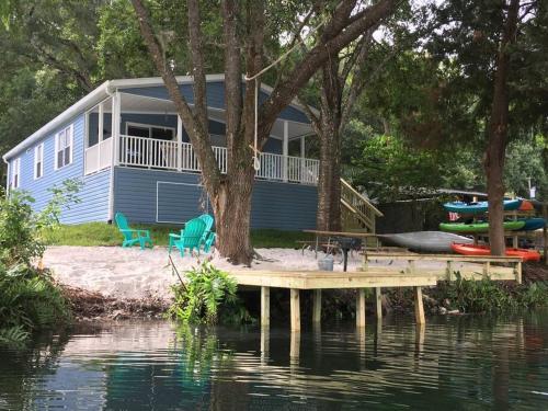 a blue house with a dock next to the water at The Chuby Mermaid - Weeki Wachee River Access Waterfront with Paddlecraft in Spring Hill