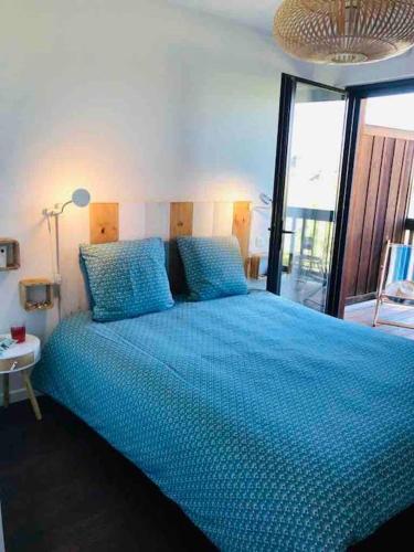- une chambre avec un lit bleu et une grande fenêtre dans l'établissement T3 duplex Port de La Teste Bassin d Arcachon, à La Teste-de-Buch