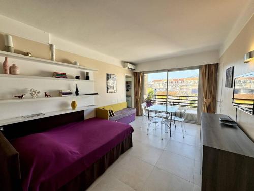 - un salon avec un lit violet et une table dans l'établissement Cannes proche Croisette - 2 pièces au calme avec terrasse, à Cannes