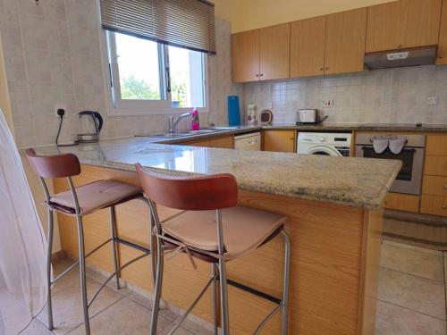 a kitchen with two bar stools and a counter top at Villa & pool 3 bedrooms 2 minutes from the beach in Maa