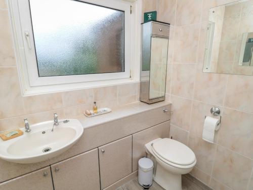 a bathroom with a sink and a toilet and a window at Crosby Cottage in Wooler