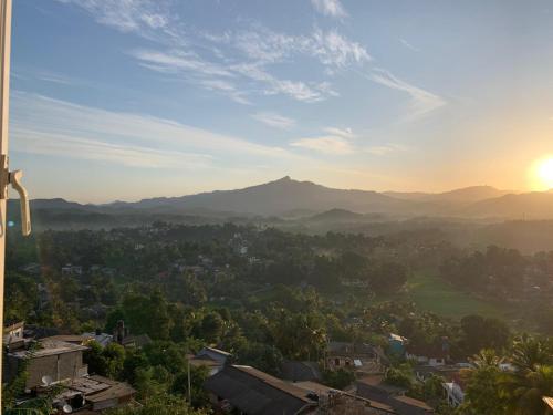 a view of a city with the sun setting behind mountains at Galkaduwa360 Villa in Kandy