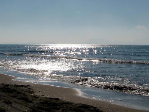 a beach with the sun reflecting on the water at B&B leperle in Torre del Greco